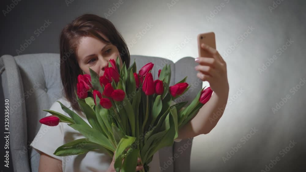 beautiful with a bouquet of red tulips takes a selfie on chair beautiful with a bouquet of red tulips takes a selfie on chair