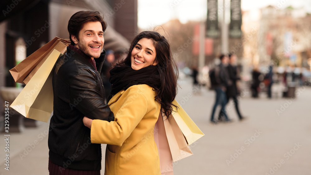 Young loving couple walking carrying paper shopping bags