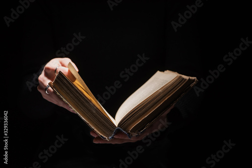 Fototapet Cropped view of woman holding holy bible isolated on black