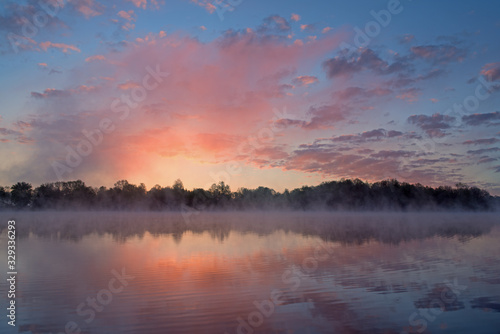Foggy landscape at dawn of Whitford Lake with reflections in calm water, Fort Custer State Park, Michigan, USA