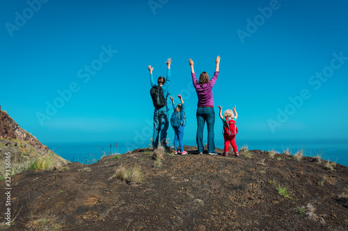 happy mom, dad with kids travel in mountains near sea