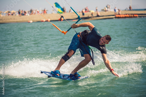 Professional kiter makes the difficult trick on a river. Kitesurfing Kiteboarding action photos man among waves quickly goes