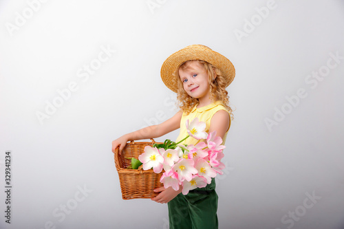 little blonde girl hold  basket of spring pink flowers on a white background