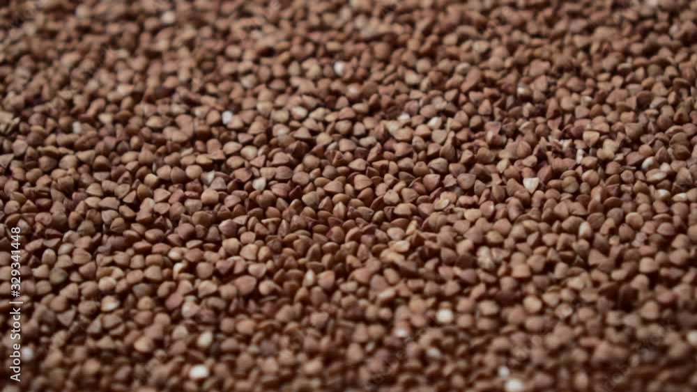 Raw buckwheat grains rotate, close-up. Top down view. Raw buckwheat grains rotate, close-up. Top down view.