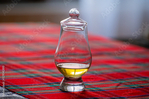Special tulip-shaped glass for tasting of Scotch whisky on distillery in Scotland, UK and red tartan