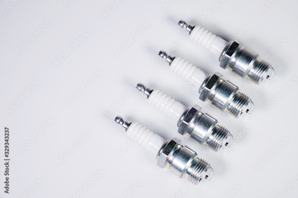 Subject shooting on a gray background. new four spark plugs, spare parts for a gasoline engine. The concept of new auto parts and maintenance Subject shooting on a gray background. new four spark plugs, spare parts for a gasoline engine. The concept of new auto parts and maintenance