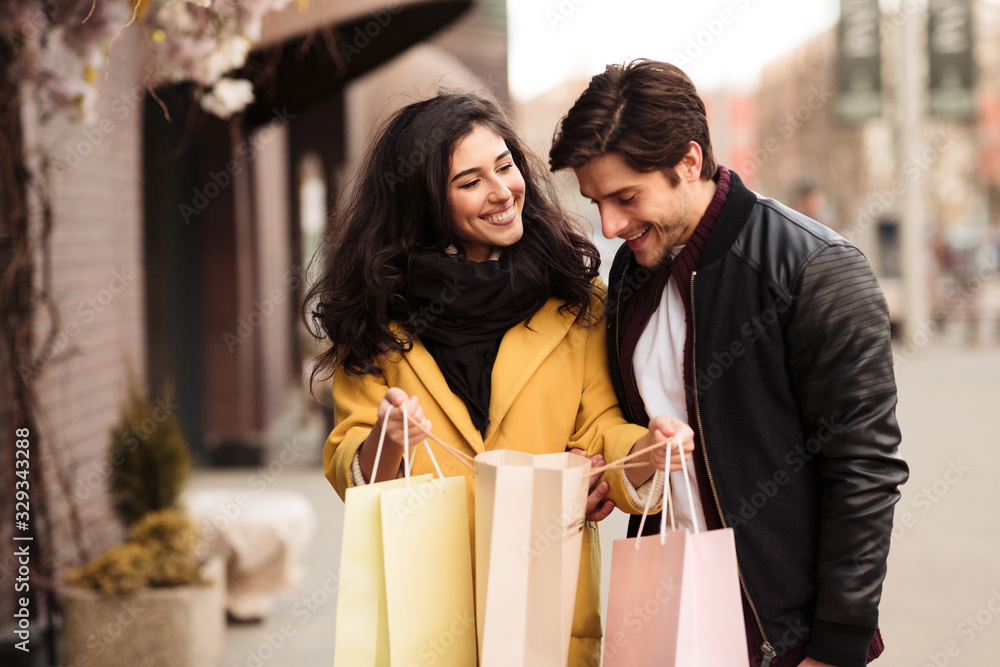 Young loving couple looking inside shopping bags