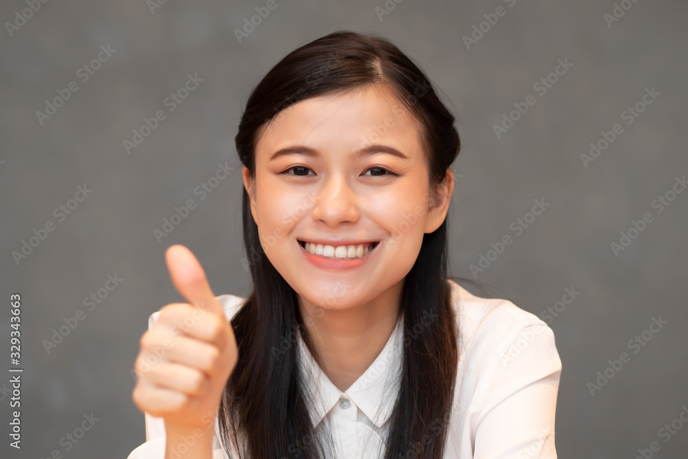 successful girl pointing thumb up; portrait of cheerful smiling woman pointing up approving, yes, ok, good, thumb up gesture; Chinese or east asian woman young adult model successful girl pointing thumb up; portrait of cheerful smiling woman pointing up approving, yes, ok, good, thumb up gesture; Chinese or east asian woman young adult model