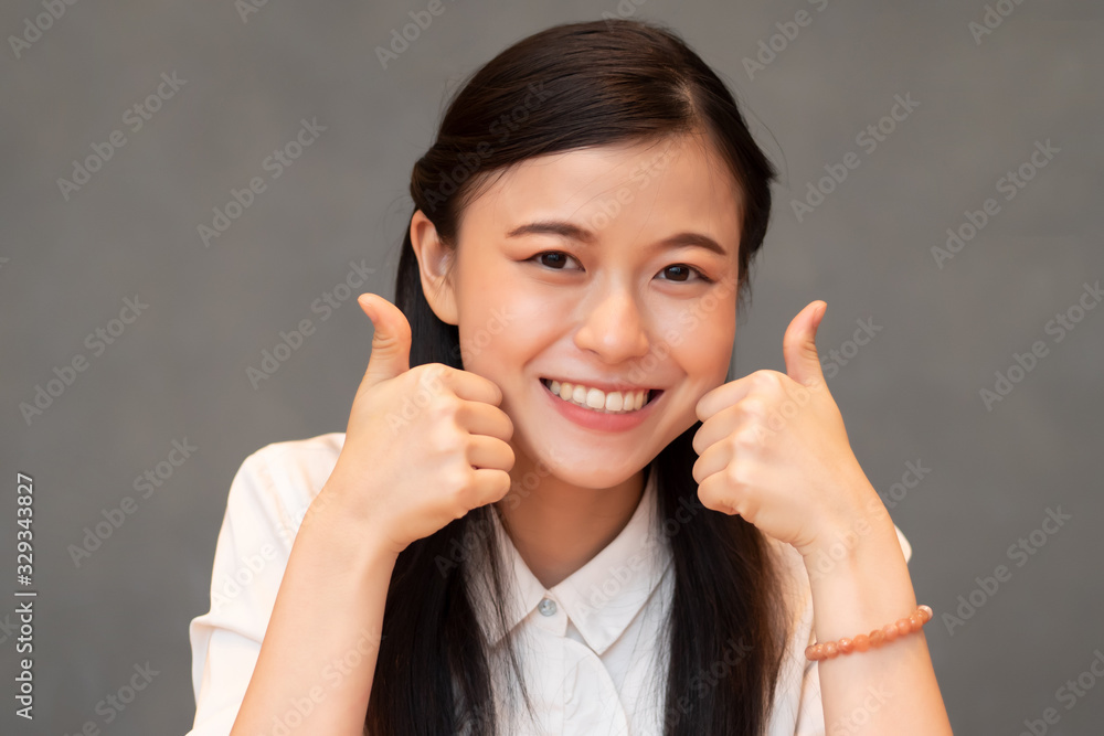 successful girl pointing two thumbs up; portrait of cheerful smiling woman pointing up approving, yes, ok, good, double thumbs up gesture; Chinese or east asian woman young adult model successful girl pointing two thumbs up; portrait of cheerful smiling woman pointing up approving, yes, ok, good, double thumbs up gesture; Chinese or east asian woman young adult model