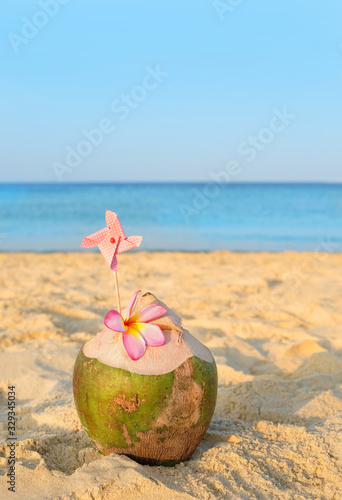 coconut cocktails on tropical beach. Summer travel, adventure and sea trip vacation concept. Sandy beach with fresh drink coconut juice decorated plumeria flower.