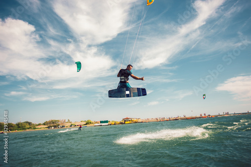 Professional kiter makes the difficult trick on a beautiful background. Kitesurfing Kiteboarding action photos man among waves quickly goes