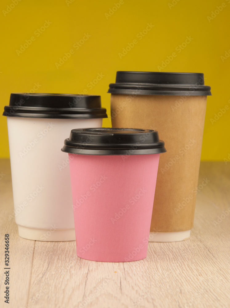 Many color disposable paper cups with lids on colorful paper background Many color disposable paper cups with lids on colorful paper background