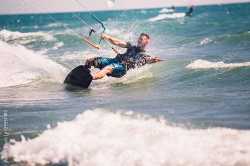 Professional kiter makes the difficult trick on a beautiful background. Kitesurfing Kiteboarding action photos man among waves quickly goes