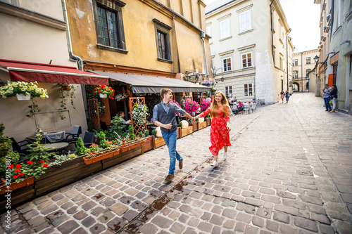 a young couple is stylishly dressed, a girl in a red dress, a man in a blue shirt and blue pants, walk the streets in Krakow Poland
