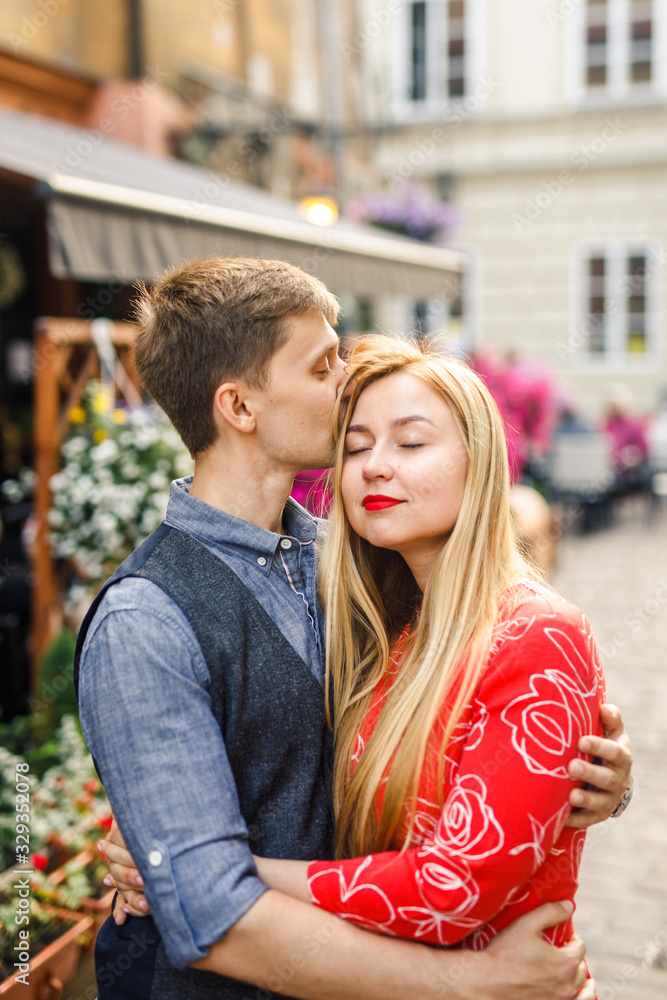 a young couple is stylishly dressed, a girl in a red dress, a man in a blue shirt and blue pants, walk the streets in Krakow Poland a young couple is stylishly dressed, a girl in a red dress, a man in a blue shirt and blue pants, walk the streets in Krakow Poland