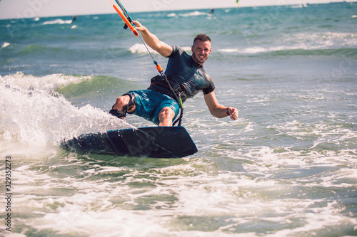 Professional kiter makes the difficult trick on a beautiful background. Kitesurfing Kiteboarding action photos man among waves quickly goes