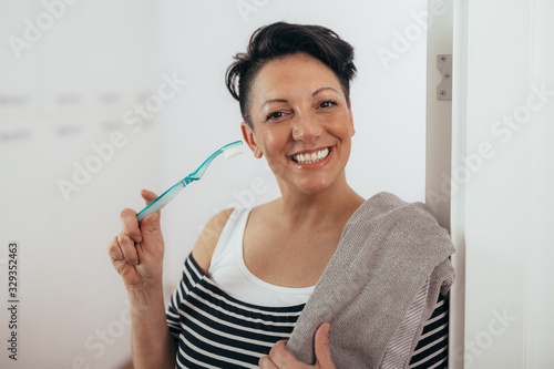 woman holding toothbrush and towel at her home