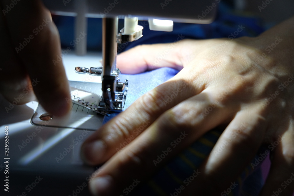 A tailor is sewing clothes with a sewing machine. A tailor is sewing clothes with a sewing machine.