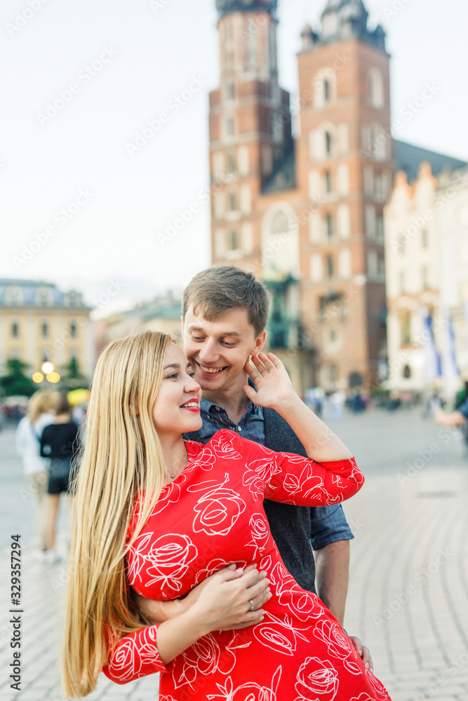 a young couple is stylishly dressed, a girl in a red dress, a man in a blue shirt and blue pants, walk the streets in Krakow Poland