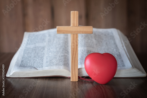 The cross and the red heart lay close together. Bible background and close-up images of the Lord Jesus' prayer Faith in the sacred power of God through prayer to Him, Christianity, Jesus