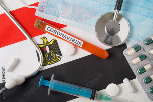 Coronavirus, nCoV concept. Top view protective breathing mask, stethoscope, syringe, pills on the flag of Egypt. photo
