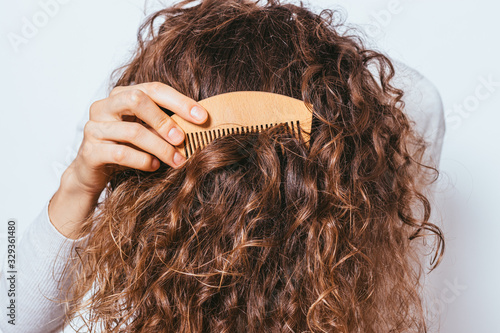 Close-up young woman combing her healthy thick curly hair photo