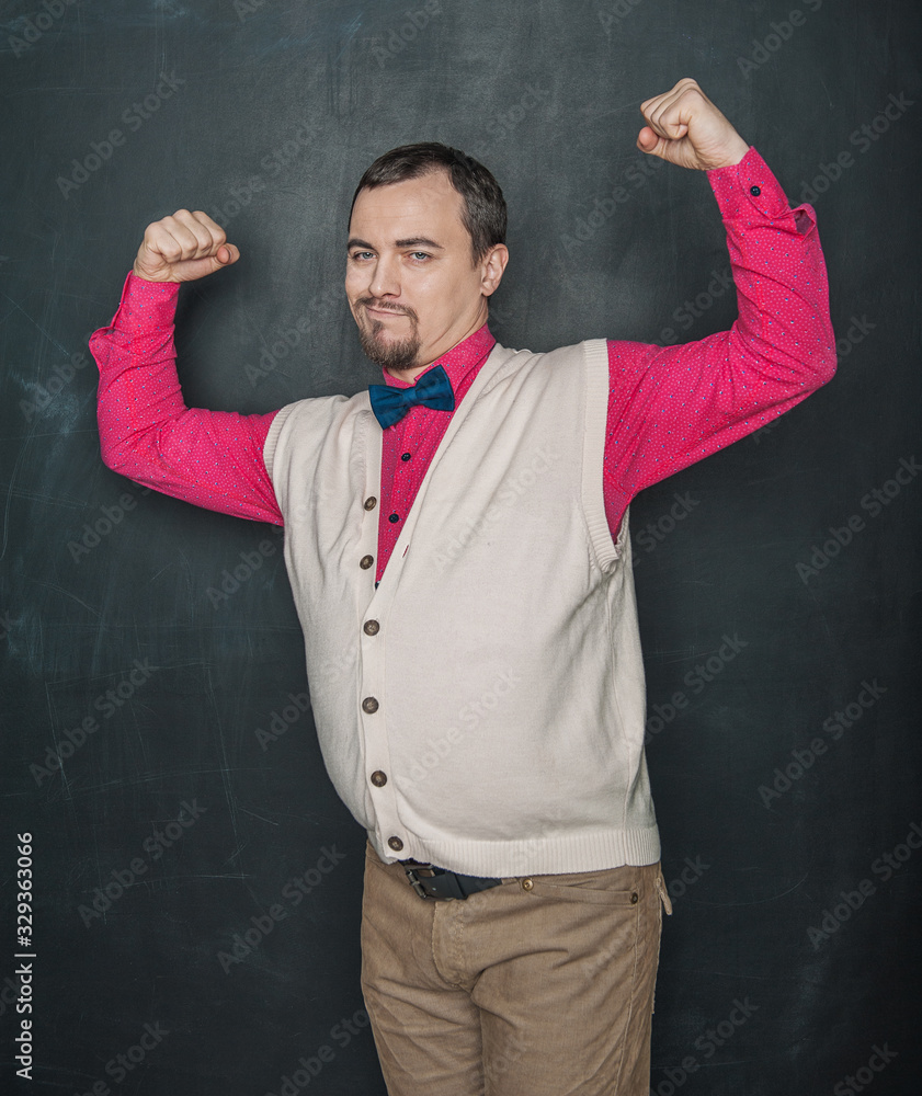 Funny nerd vintage style man flexing his muscle on blackboard