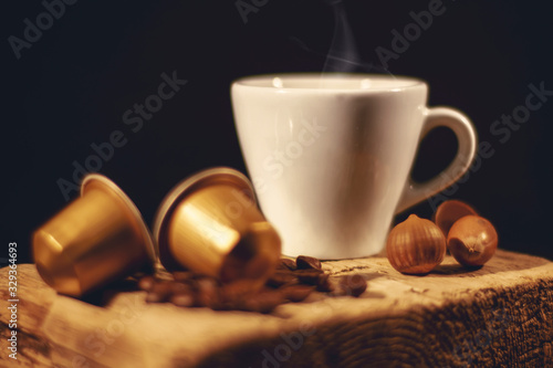 Cup of coffee in woodden background with coffee capusles ands coffee beans