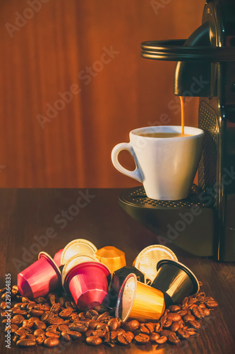 Cup of coffee amd coffee machine in woodden background with coffee capusles ands coffee beans