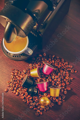 Cup of coffee amd coffee machine in woodden background with coffee capusles ands coffee beans