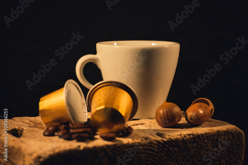 Cup of coffee in woodden background with coffee capusles ands coffee beans