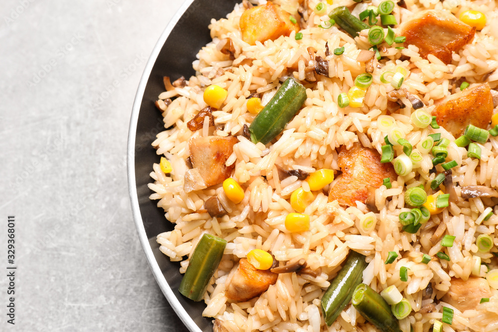 Delicious rice pilaf with chicken and vegetables on light grey table, closeup