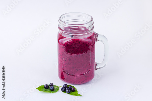 Blueberry smoothie in mason jar mug with mint and some fresh berries on white  background. The concept of proper nutrition and healthy eating. Organic and vegetarian drink. Close up, copy space for