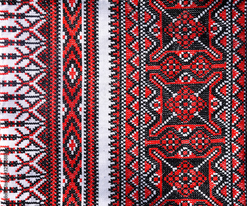 Ukrainian folk hand embroidery. Embroidered ornament with red-black threads on white fabric.