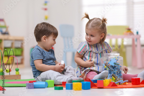 Cute little children playing together on floor at home