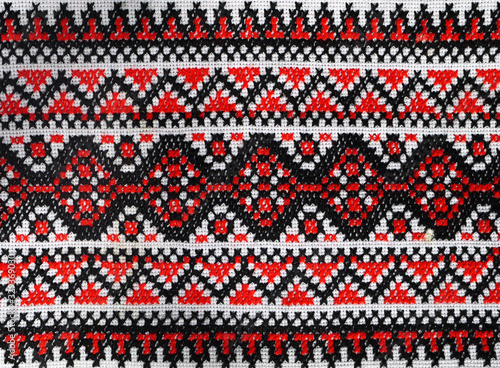 Ukrainian folk hand embroidery. Embroidered ornament with red-black threads on white fabric.