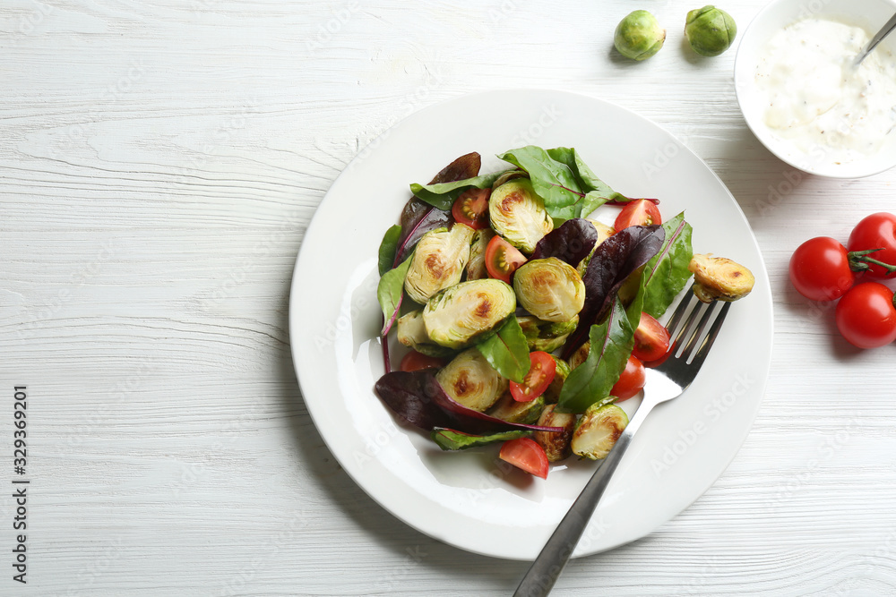Delicious salad with roasted Brussels sprouts on white wooden table, flat lay