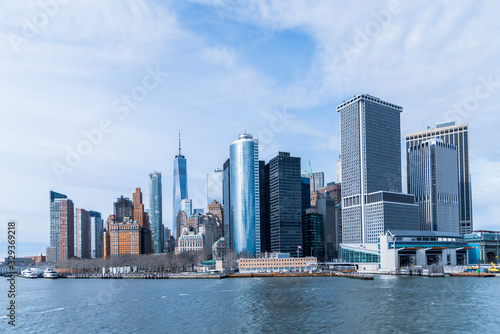 Lower Manhattan skyline viewed from the Hudson river under partly cloudy mid day sun light. © Richard