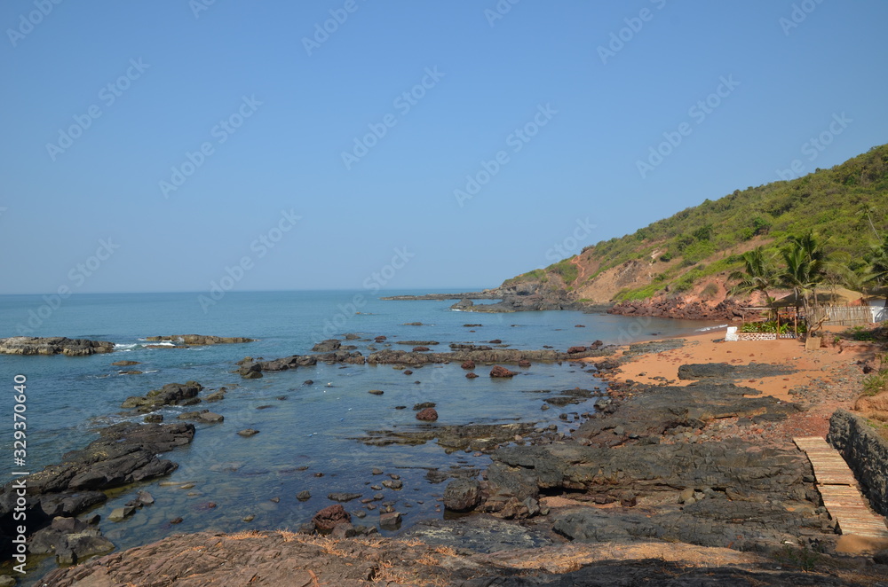 Nature in North Goa. India. Red earth, volcanic rocks and boulders. Beautiful blue sea. Vacation concept in India.