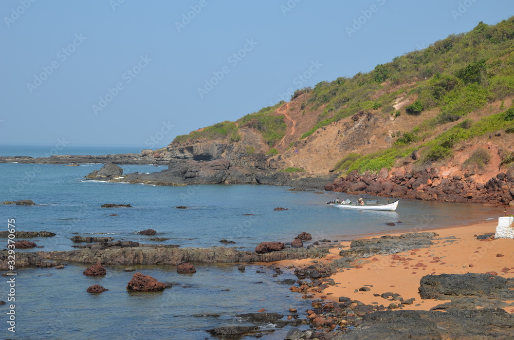 Nature in North Goa. India. Red earth, volcanic rocks and boulders. Beautiful blue sea. Vacation concept in India.