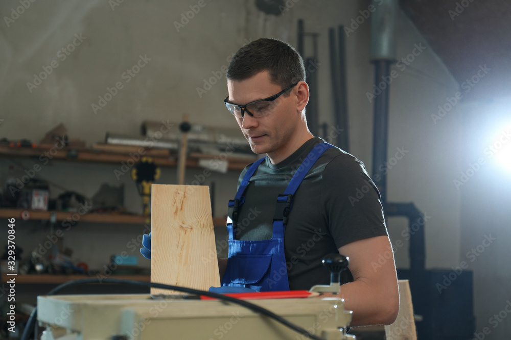 Professional carpenter with wooden board in workshop Professional carpenter with wooden board in workshop