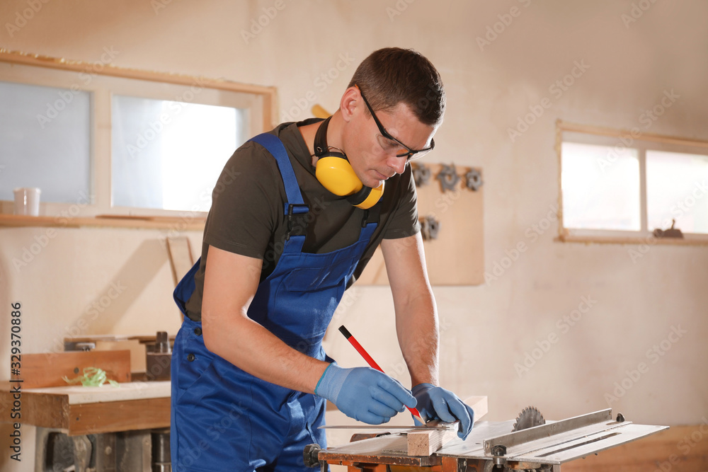 Professional carpenter making mark on wooden bar in workshop Professional carpenter making mark on wooden bar in workshop