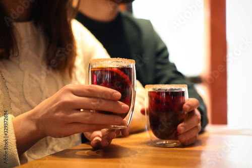 Lovely couple with tasty mulled wine at table in cafe  closeup