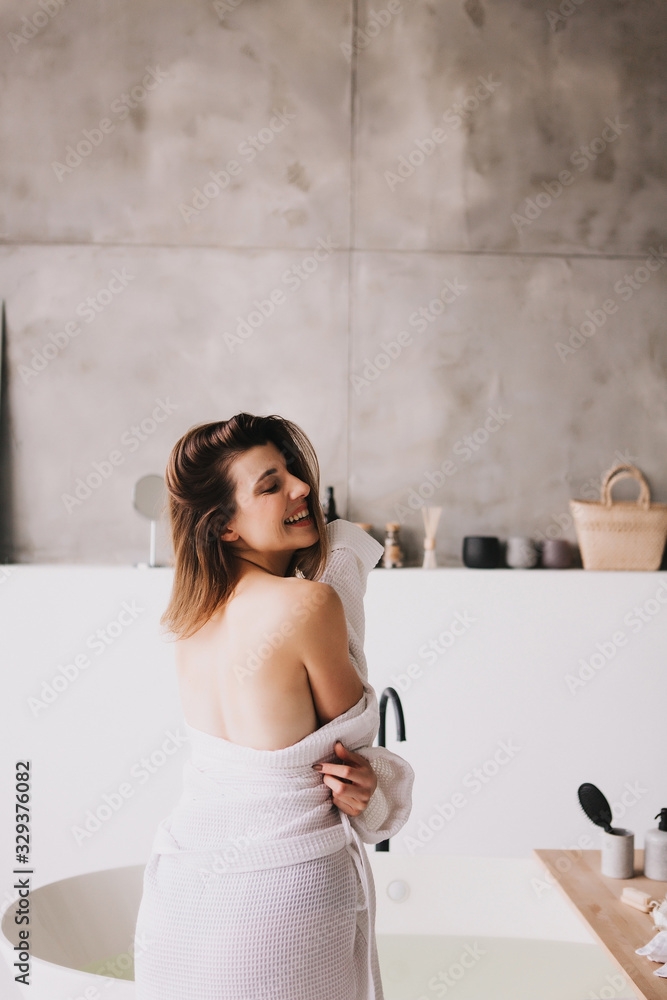 Beautiful woman relaxing in white bathrobe near bath Beautiful woman relaxing in white bathrobe near bath