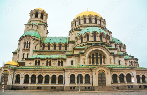 St. Alexander Nevsky Cathedral, Sofia, Bulgaria. Frontal. The domes are golden and oval, the lower domes are green. At the bottom there are two doors with stairs. The windows are neo Byzantine photo