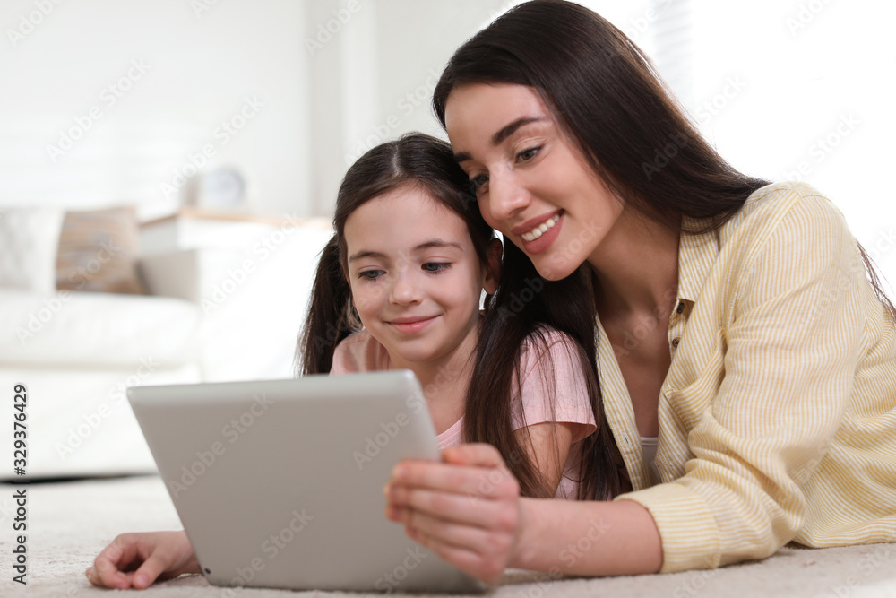 Mother and daughter reading E-book together at home Mother and daughter reading E-book together at home