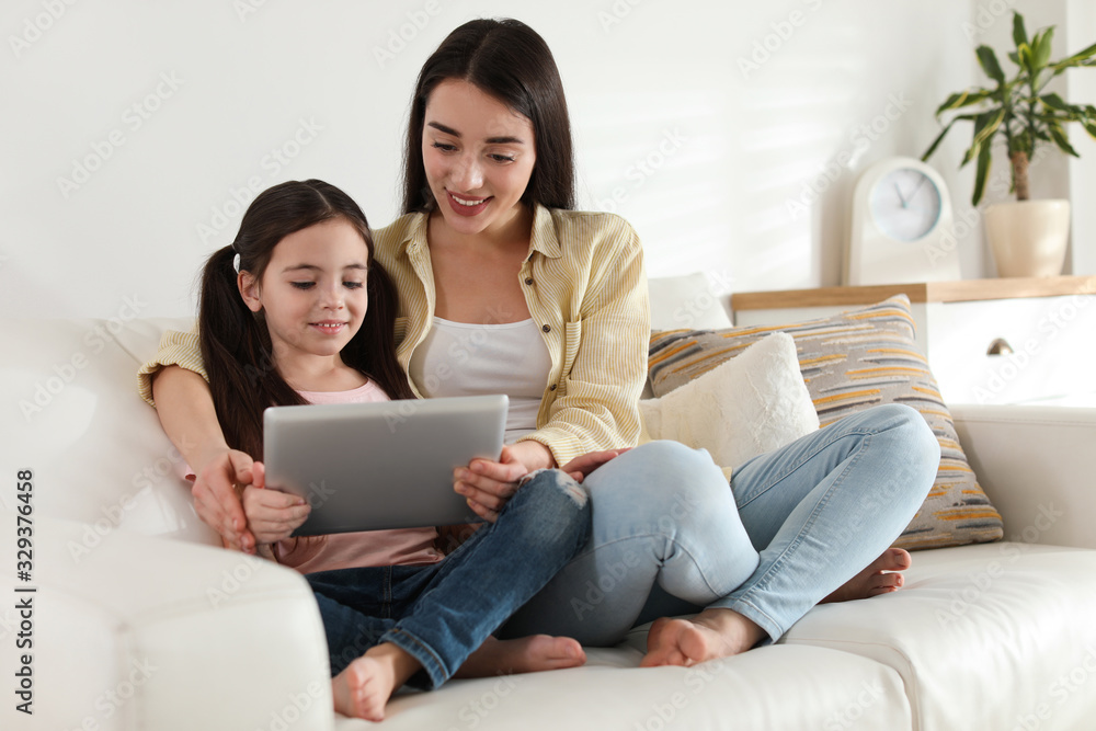 Mother and daughter reading E-book together at home