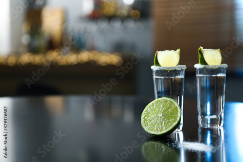Mexican Tequila with salt and lime slices on black table at bar. Space for text