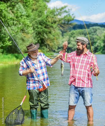 family reunion time. father and son fishing. male friendship. family bonding. summer weekend. two fishermen with fishing rods. trout bait. mature men fisher. hobby and sport activity