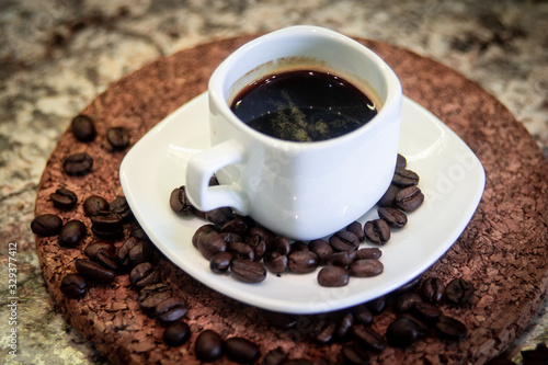 A small cup of espresso and coffee beans on a stand